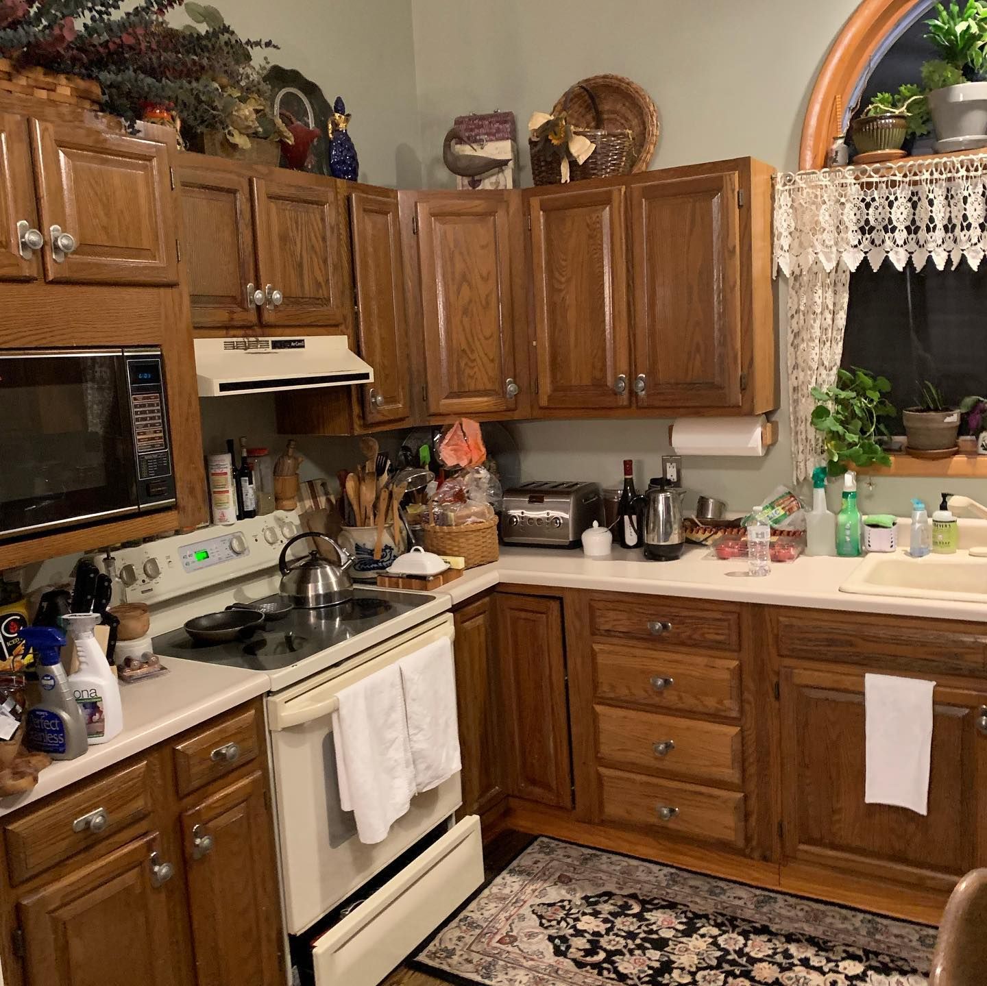 Kitchen with oak cabinets, white appliances, and countertop with various items.