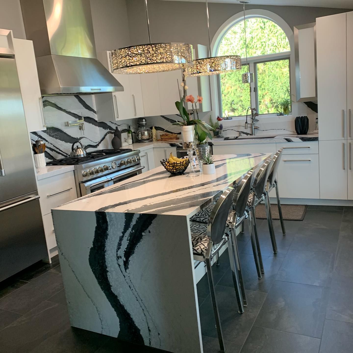 Modern white kitchen with black and white countertop island and stainless steel appliances.
