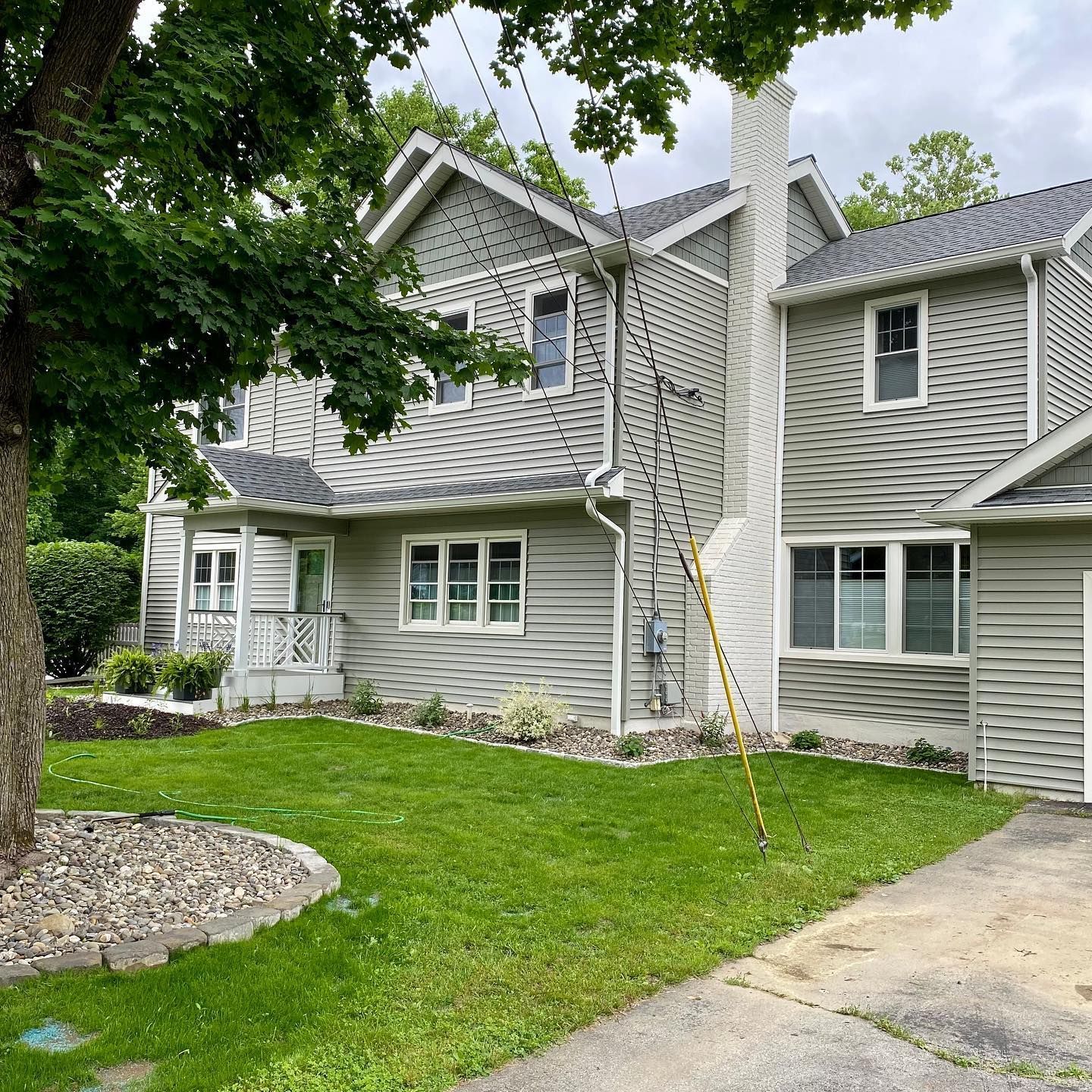 Gray house with white trim, chimney, and green lawn. Tree on left.