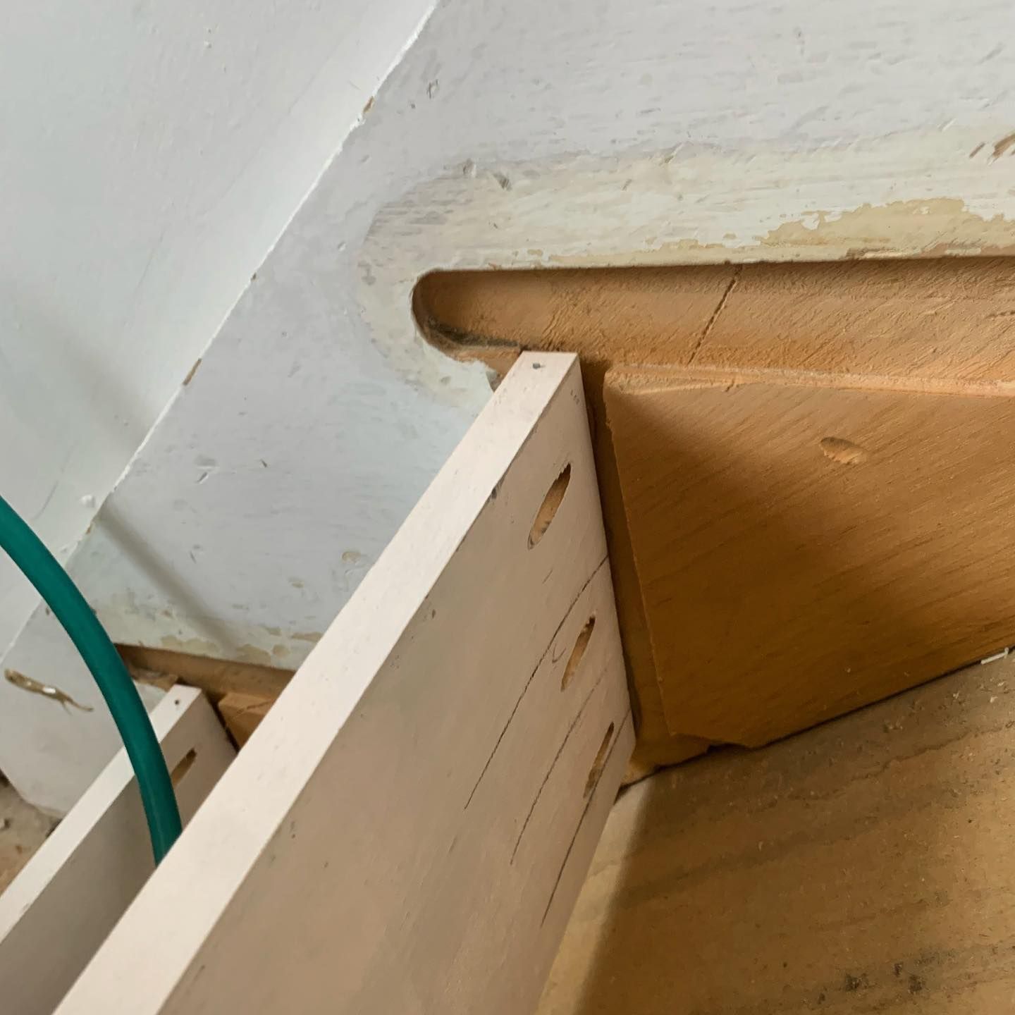White cabinet being installed, with a rounded opening in the wall.