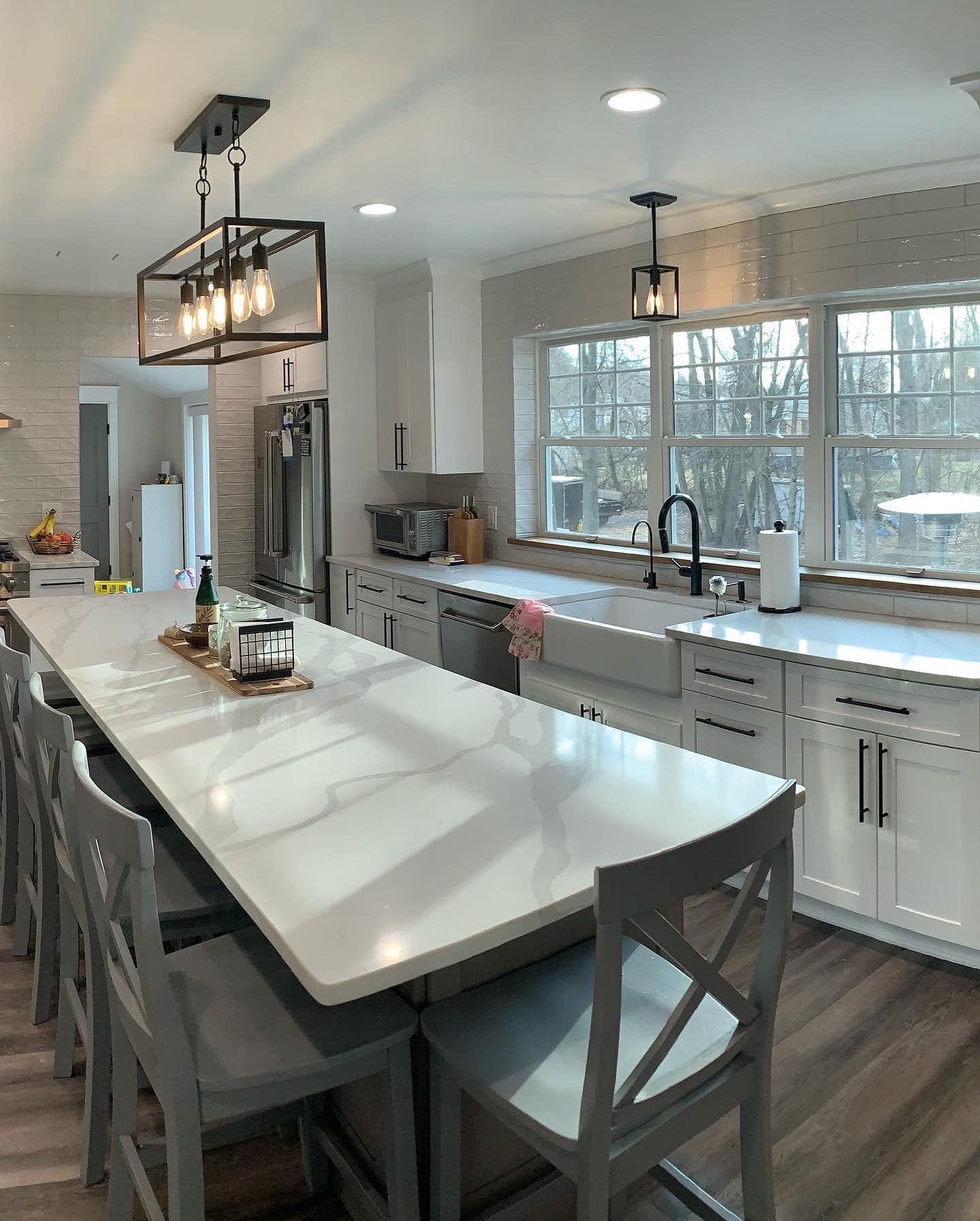 Modern kitchen with white cabinets, long island, and pendant lights.