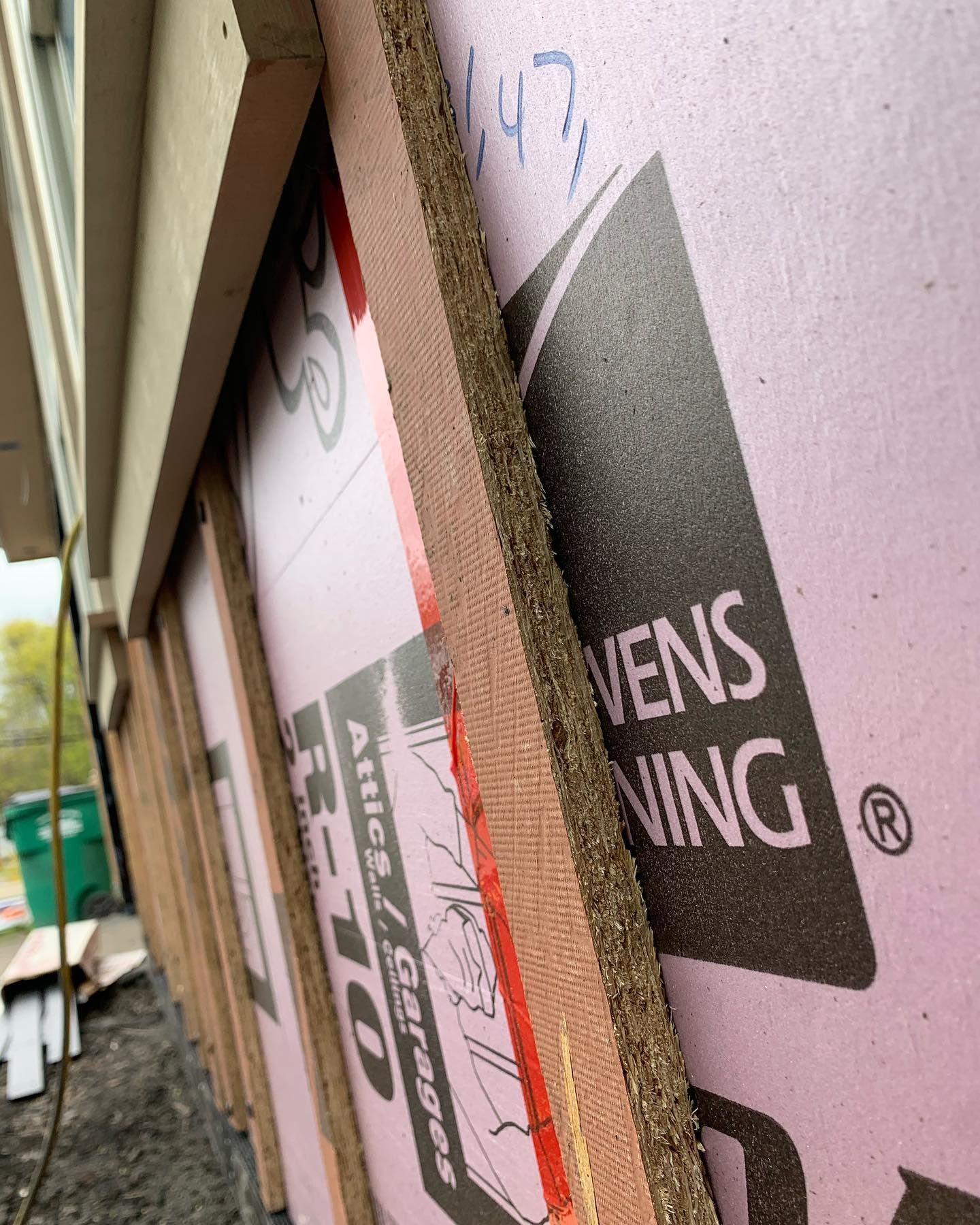 Construction of building exterior: pink foam insulation panels, brown wood framing.