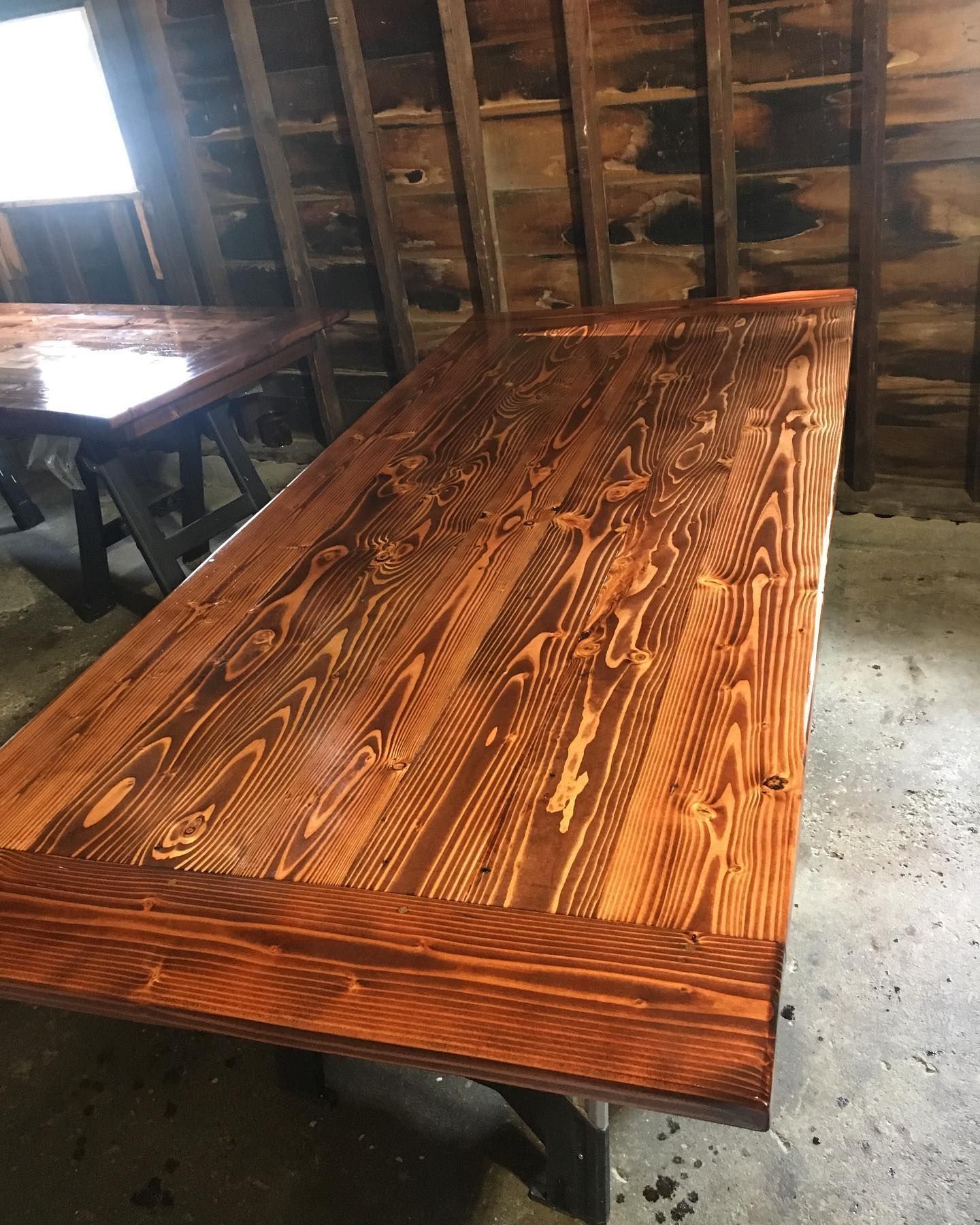 Wood table with rich brown stain, set on sawhorses, in a rustic setting.