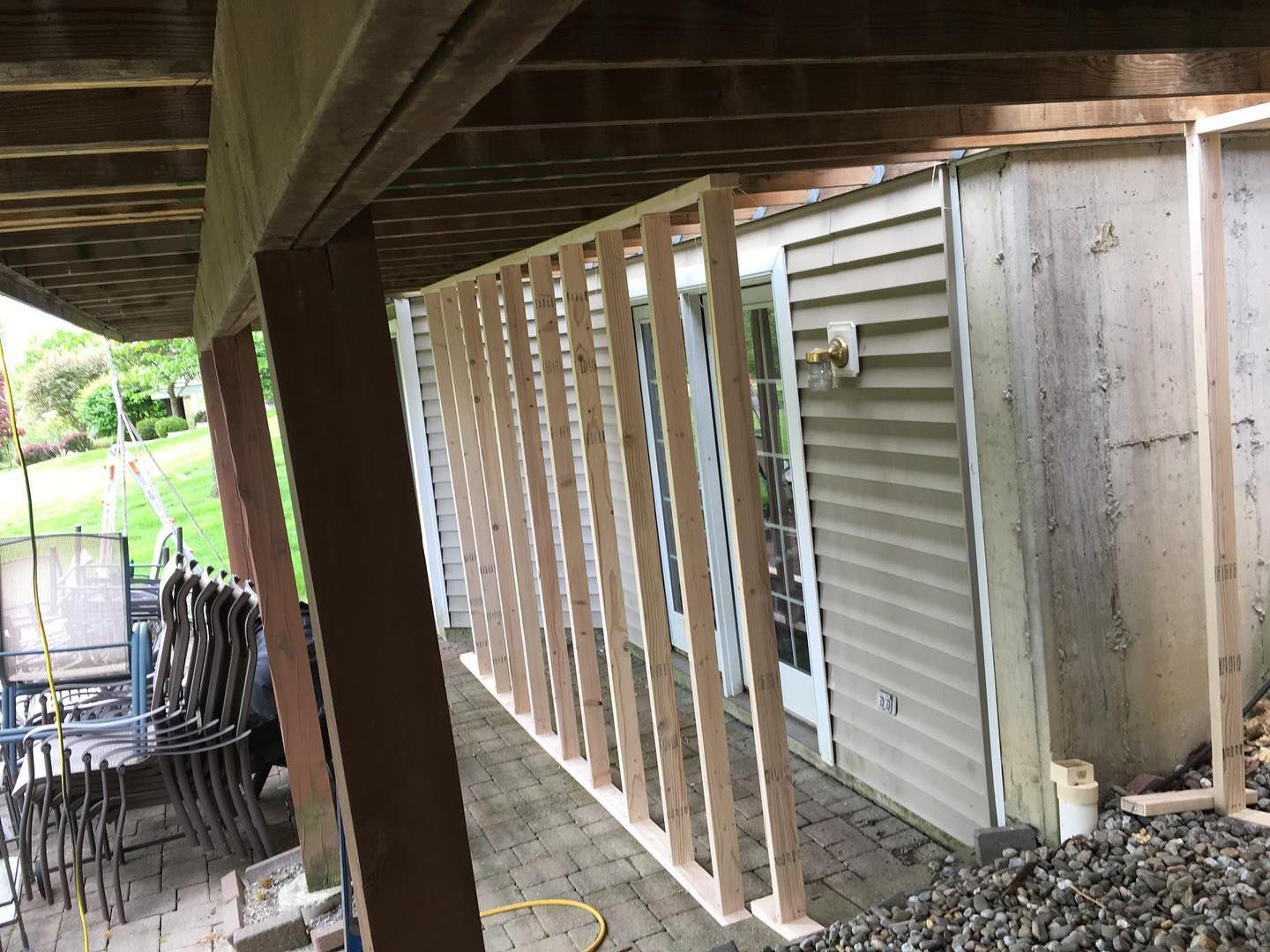 Wooden railing under construction, set against a house with a patio.