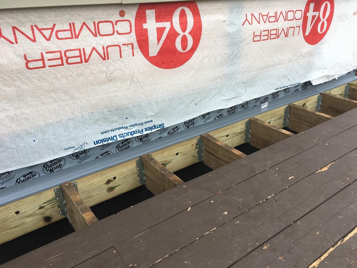 Deck construction with a flashing detail, 84 Lumber Company logo visible.