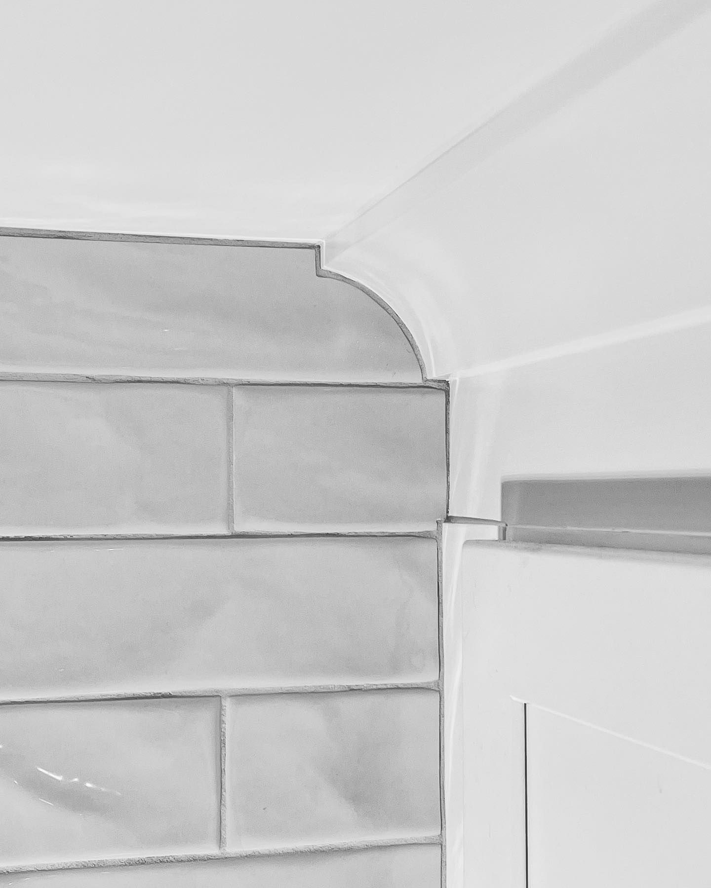 Gray tiled corner with curved white molding and white cabinet edge.