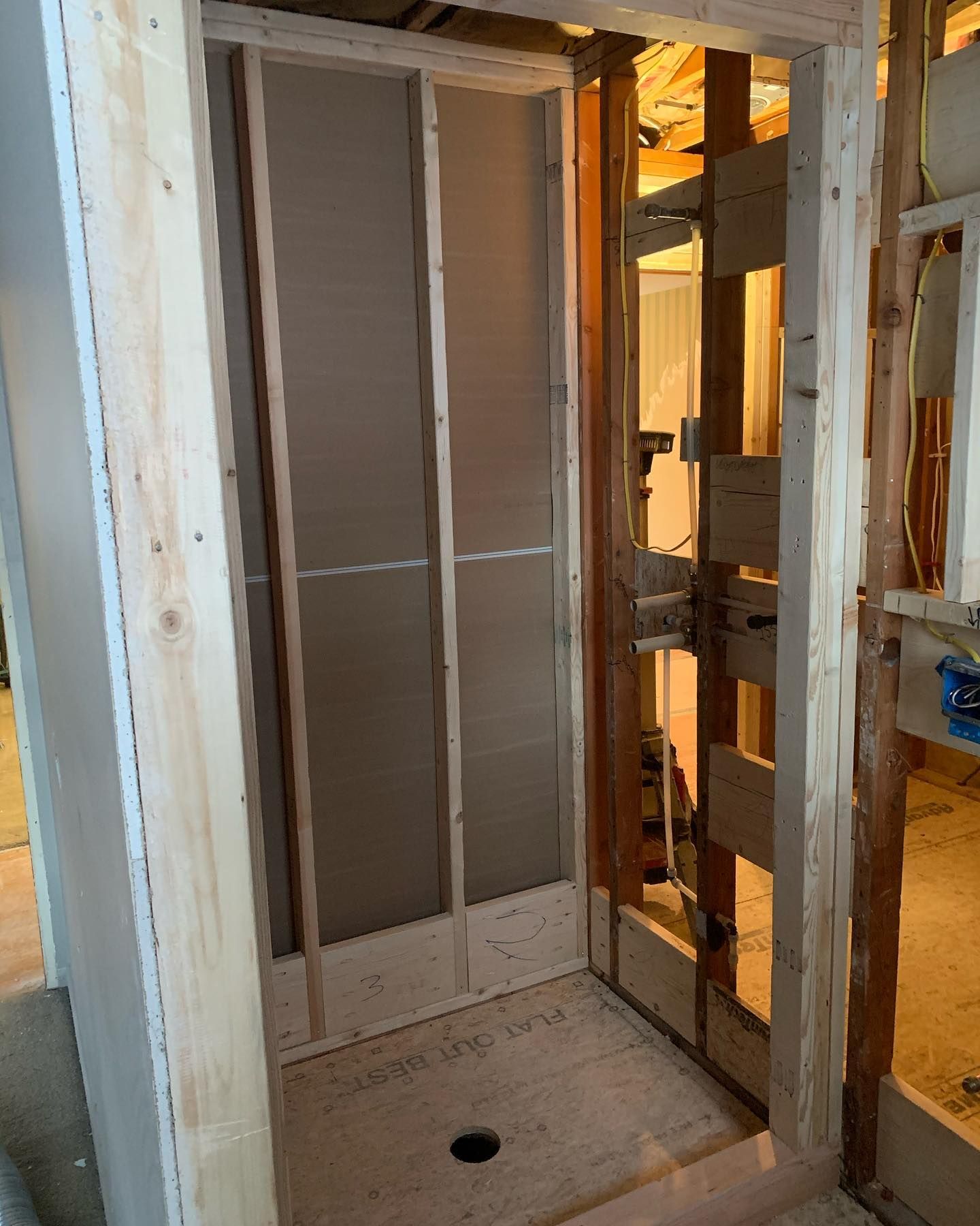 Framed shower stall under construction. Grey cement backer board on interior walls.
