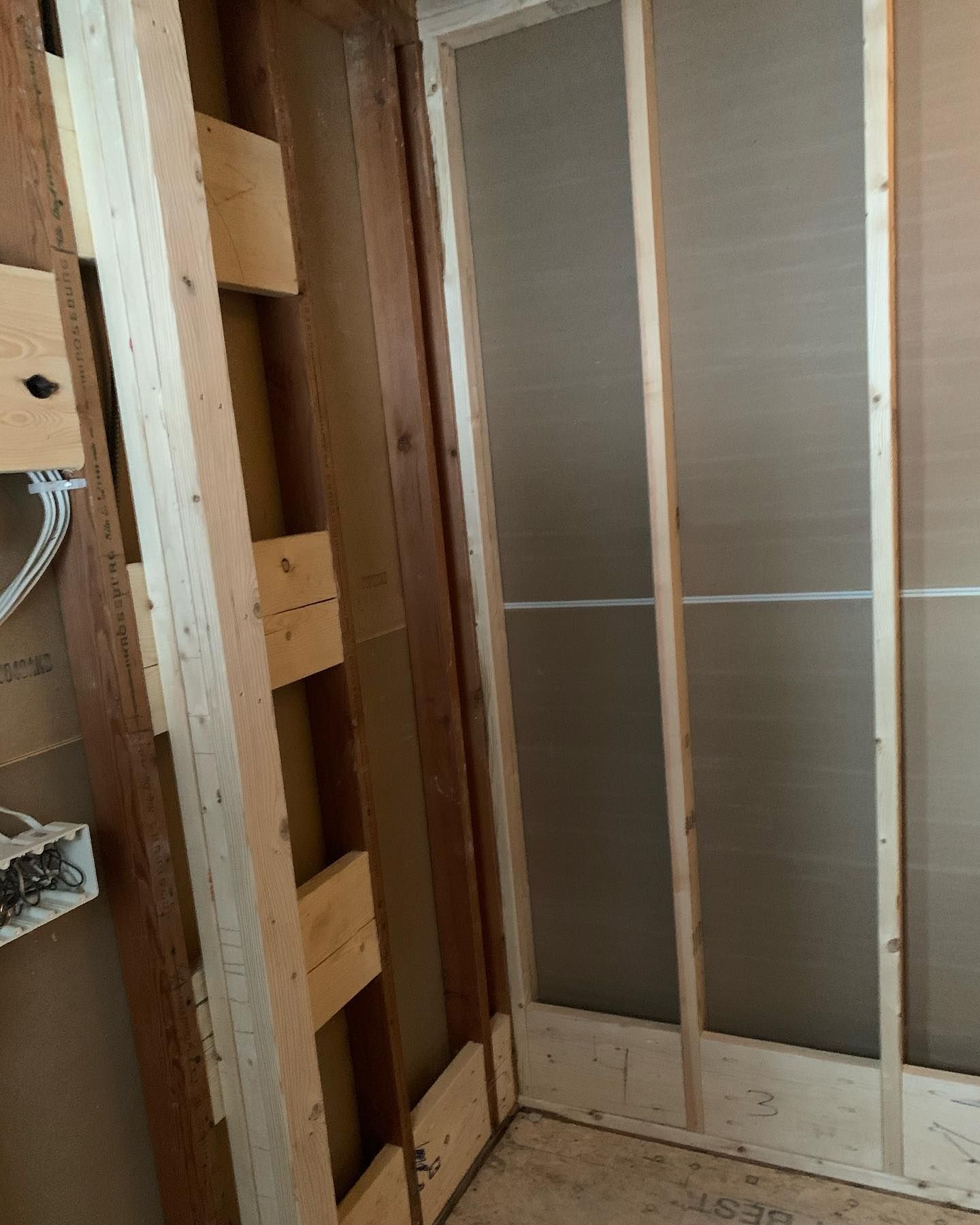 Interior wall framing under construction. Wooden studs with exposed drywall.