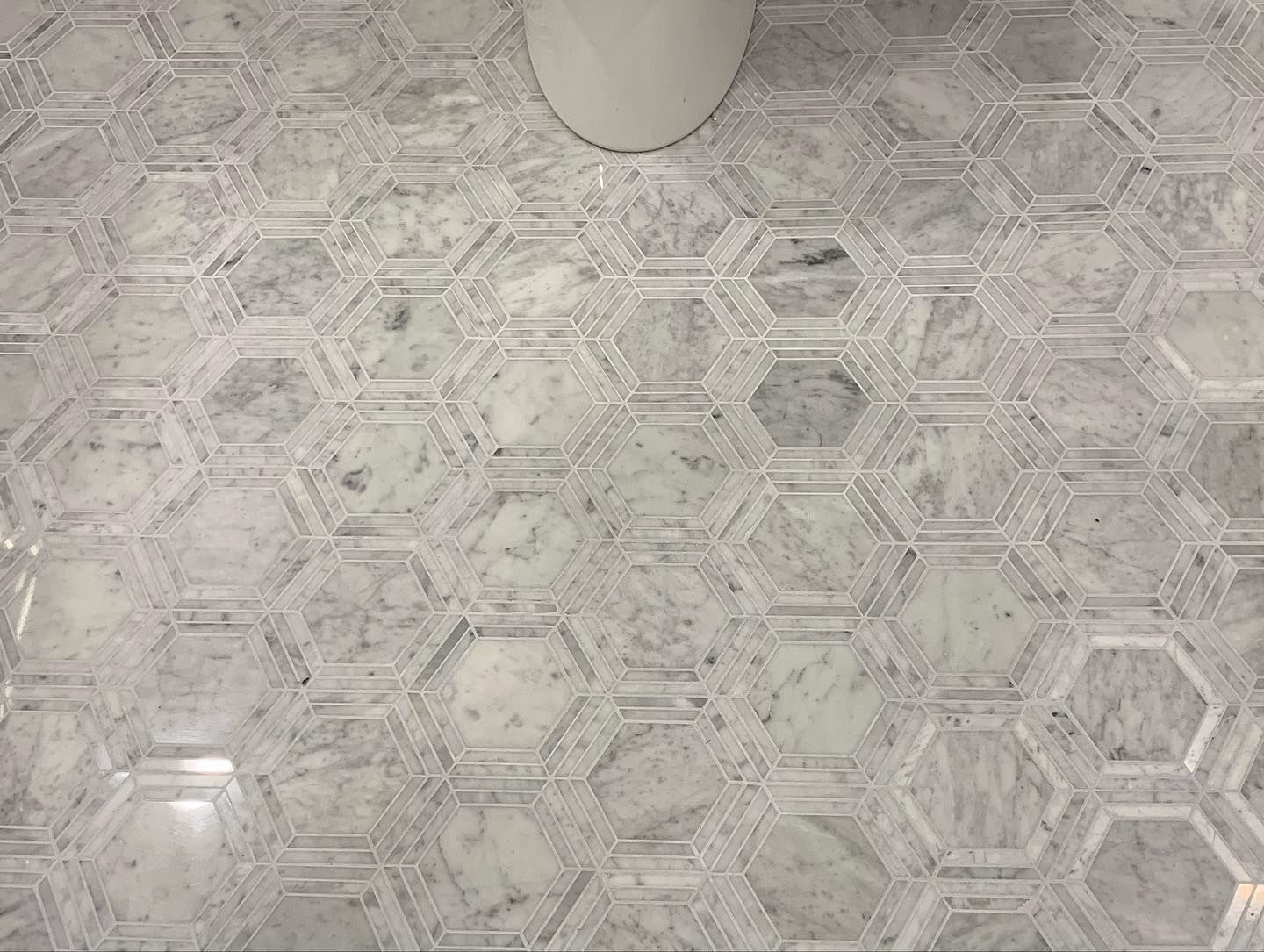 White marble hexagon tile floor under a white toilet.