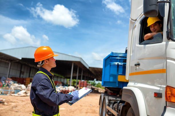 A man in a hard hat is standing next to a truck.