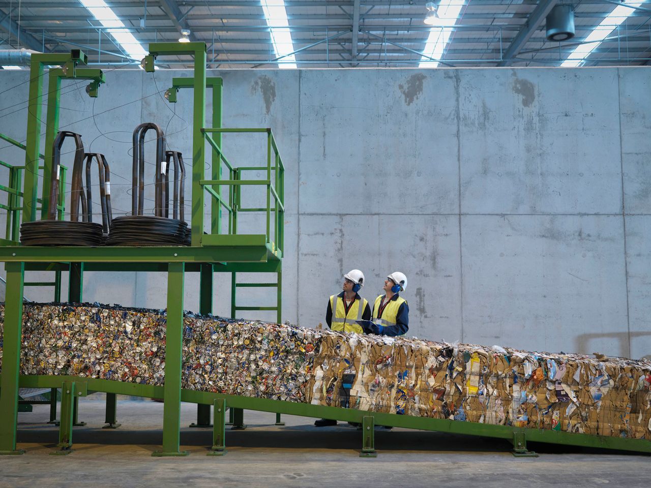 Two men are standing next to a conveyor belt in a warehouse.