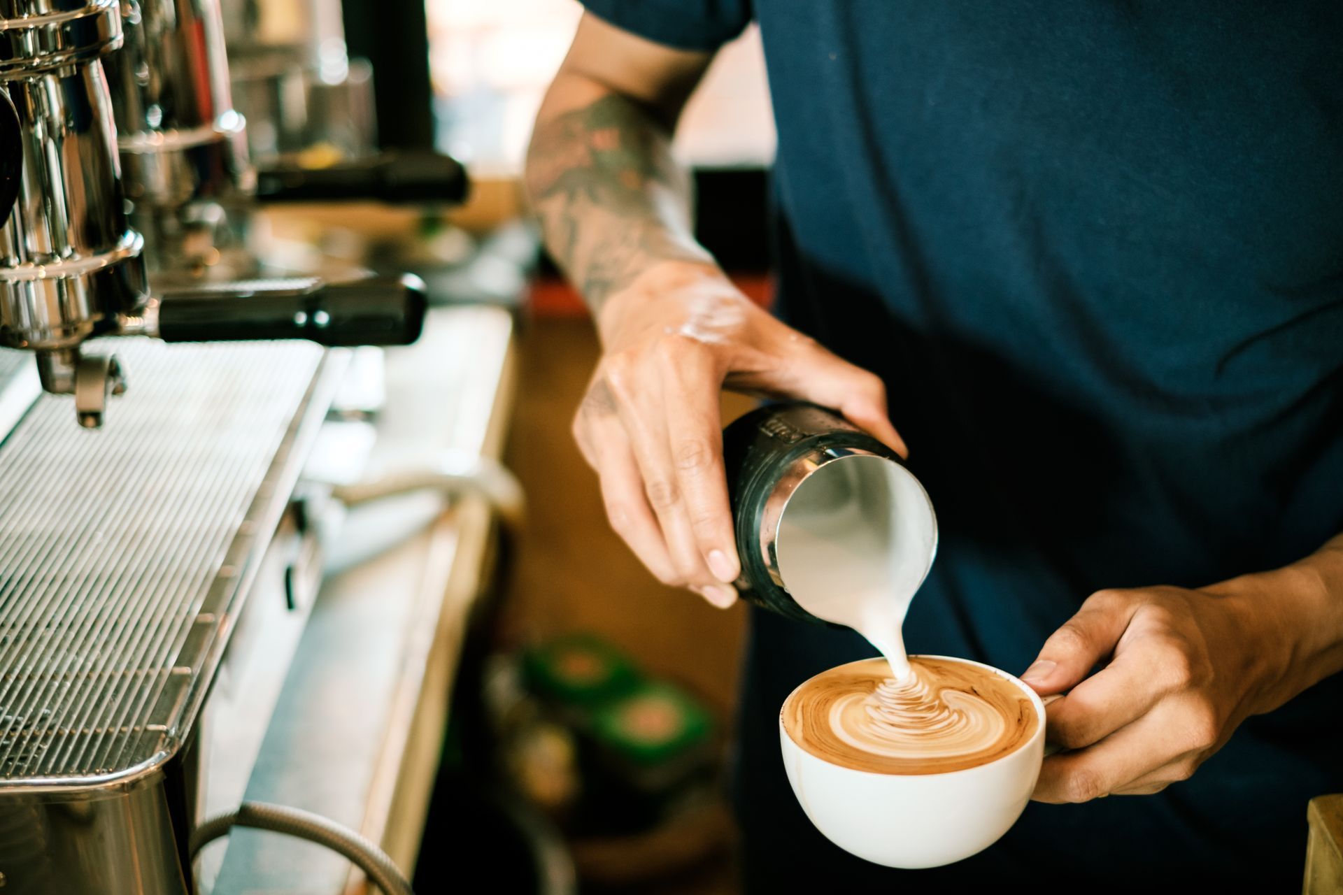 A barista is pouring milk into a cup of coffee.