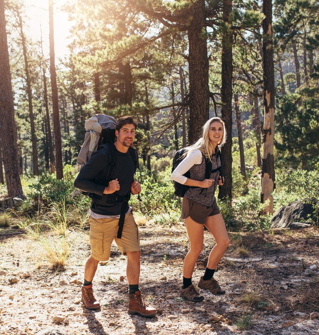 A man and a woman are hiking through a forest.