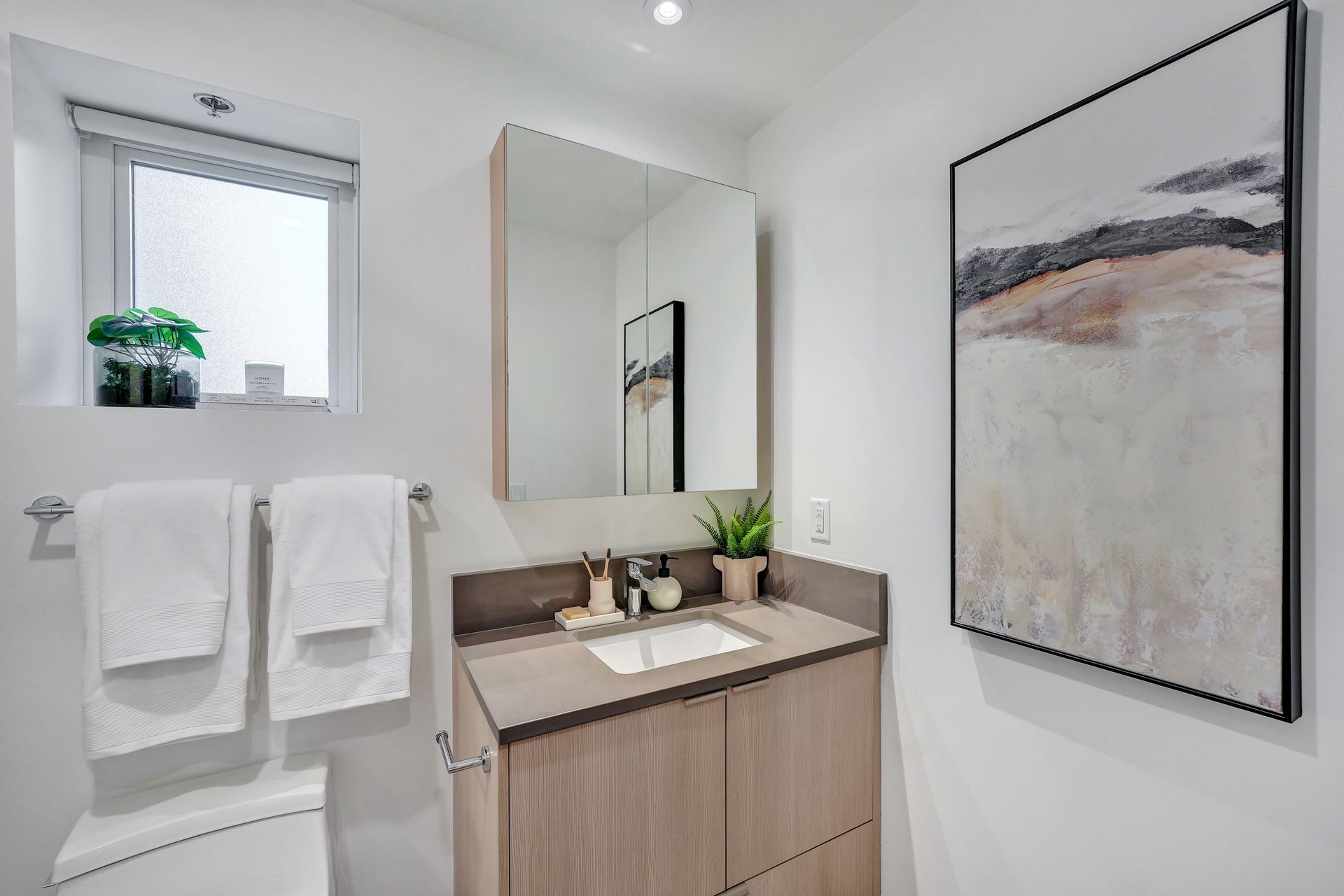 A man is standing in a kitchen drinking coffee and looking at a tablet.
