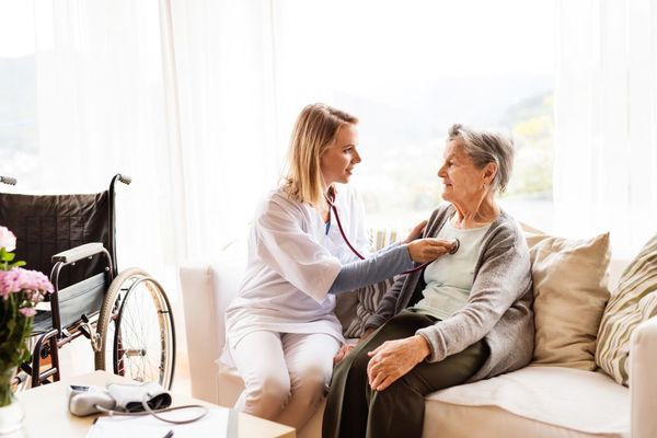 A Nurse is Listening to an Elderly Woman 's Heartbeat With a Stethoscope — Home Nursing Services In Macquarie, NSW
