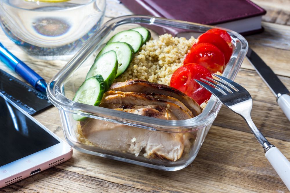A Glass Container Filled With Food And A Fork On A Wooden Table — Home Nursing Services In Lake Cathie, NSW