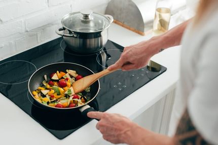 A Person is Cooking Vegetables in a Frying Pan on a Stove — Home Nursing Services In Macquarie, NSW