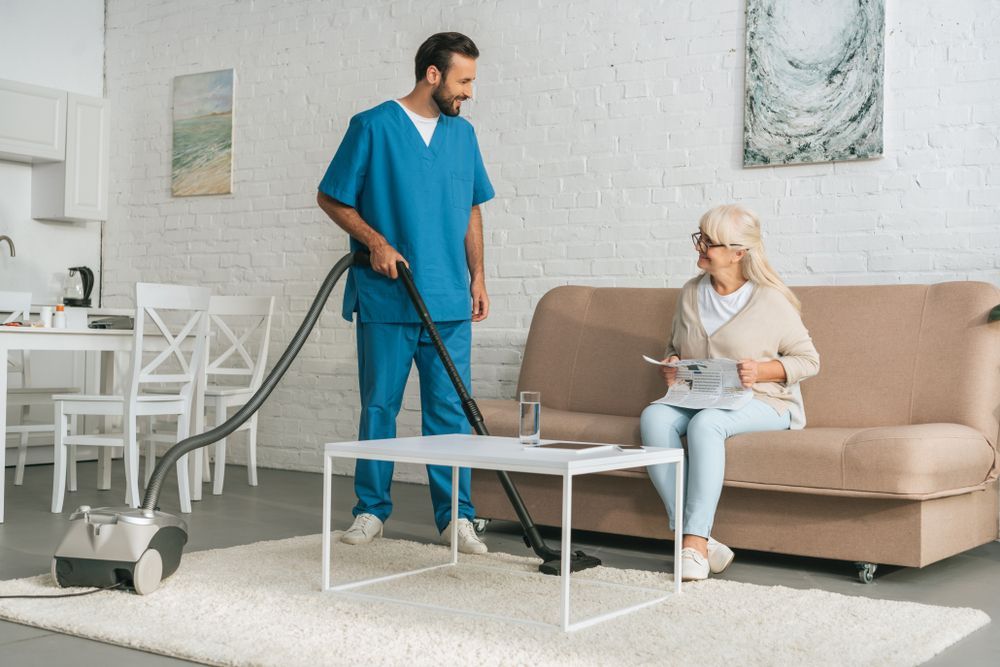 A Nurse Is Vacuuming The Floor In A Living Room — Home Nursing Services In Toronto, NSW