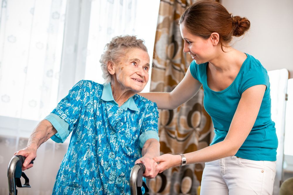 A Woman Is Helping An Elderly Woman With A Walker — Home Nursing Services In Williamtown, NSW