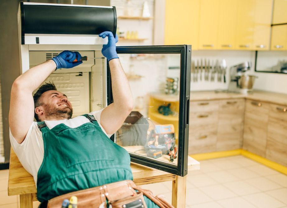 A Man is Installing a Light Fixture on a Ceiling — Home Nursing Services In Port Macquarie, NSW