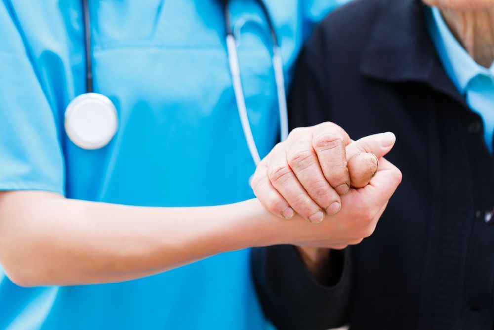 A Nurse Is Holding The Hand Of An Elderly Woman — Home Nursing Services In Fennell Bay, NSW