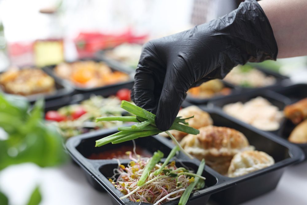 A Person Wearing Black Gloves Is Preparing Food — Home Nursing Services In Dora Creek, NSW