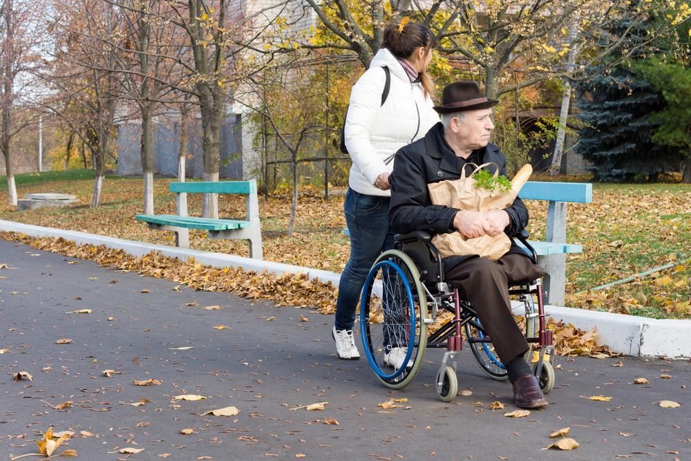 Woman Pushes Wheelchair Of An Elderly Man With Grocery — Home Nursing Services In Kew, NSW