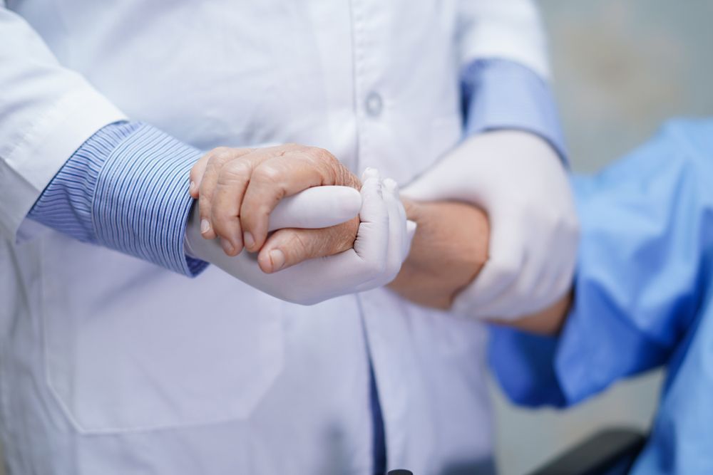 A Doctor Is Holding The Hand Of An Elderly Woman — Home Nursing Services In Toronto, NSW