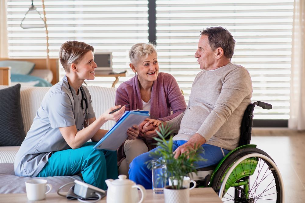 A Nurse is Talking to an Elderly Couple and a Man in a Wheelchair — Home Nursing Services In Macquarie, NSW