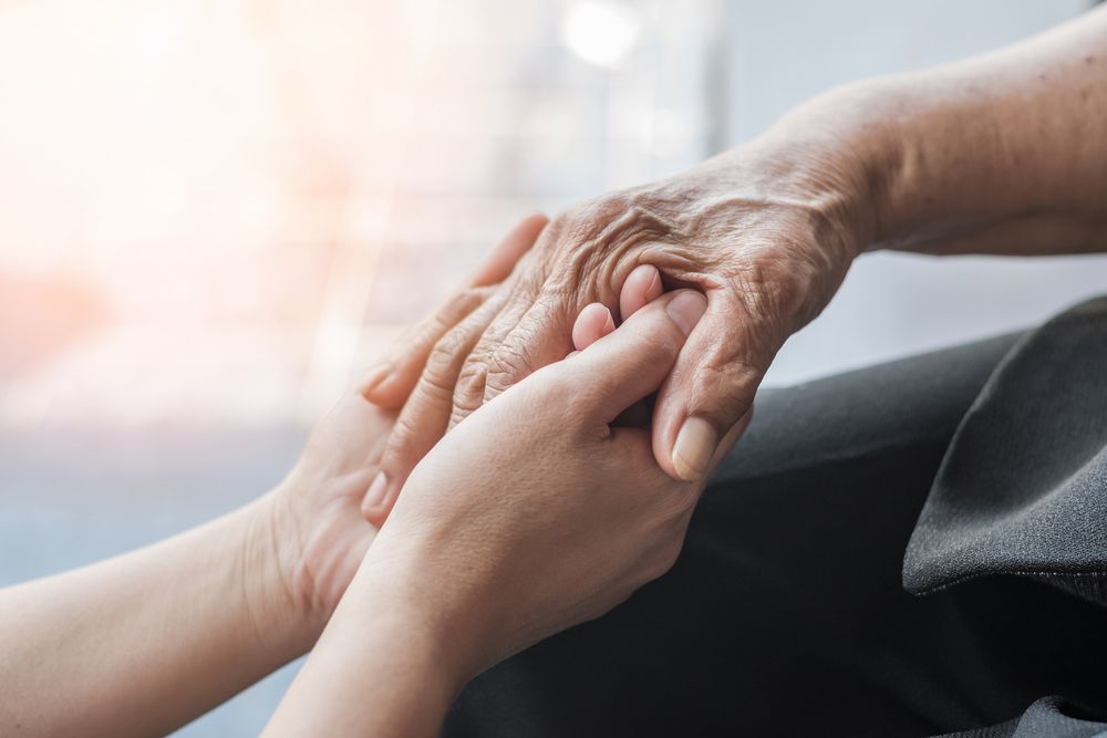 A Young Woman Is Holding The Hand Of An Older Woman — Home Nursing Services In Toronto, NSW