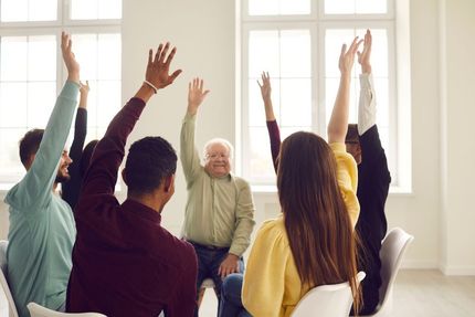 A Group of People Are Sitting in a Circle With Their Hands in the Air — Home Nursing Services In Macquarie, NSW