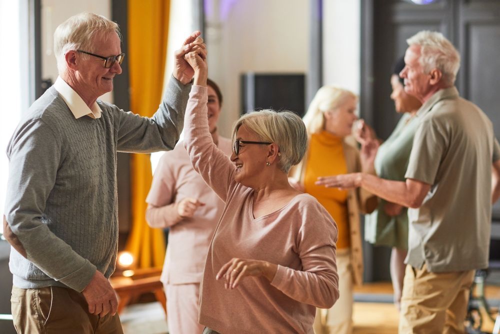 A Group Of Elderly People Are Dancing Together In A Living Room — Home Nursing Services In Dora Creek, NSW