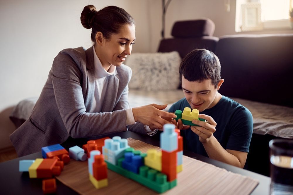 A Woman and a Boy Are Playing With Blocks at a Table — Home Nursing Services In Macquarie, NSW