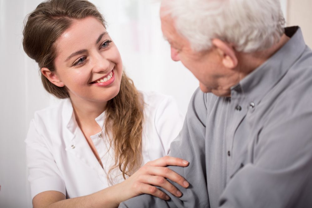 A Nurse Is Talking To An Elderly Man And Smiling — Home Nursing Services In Warners Bay, NSW