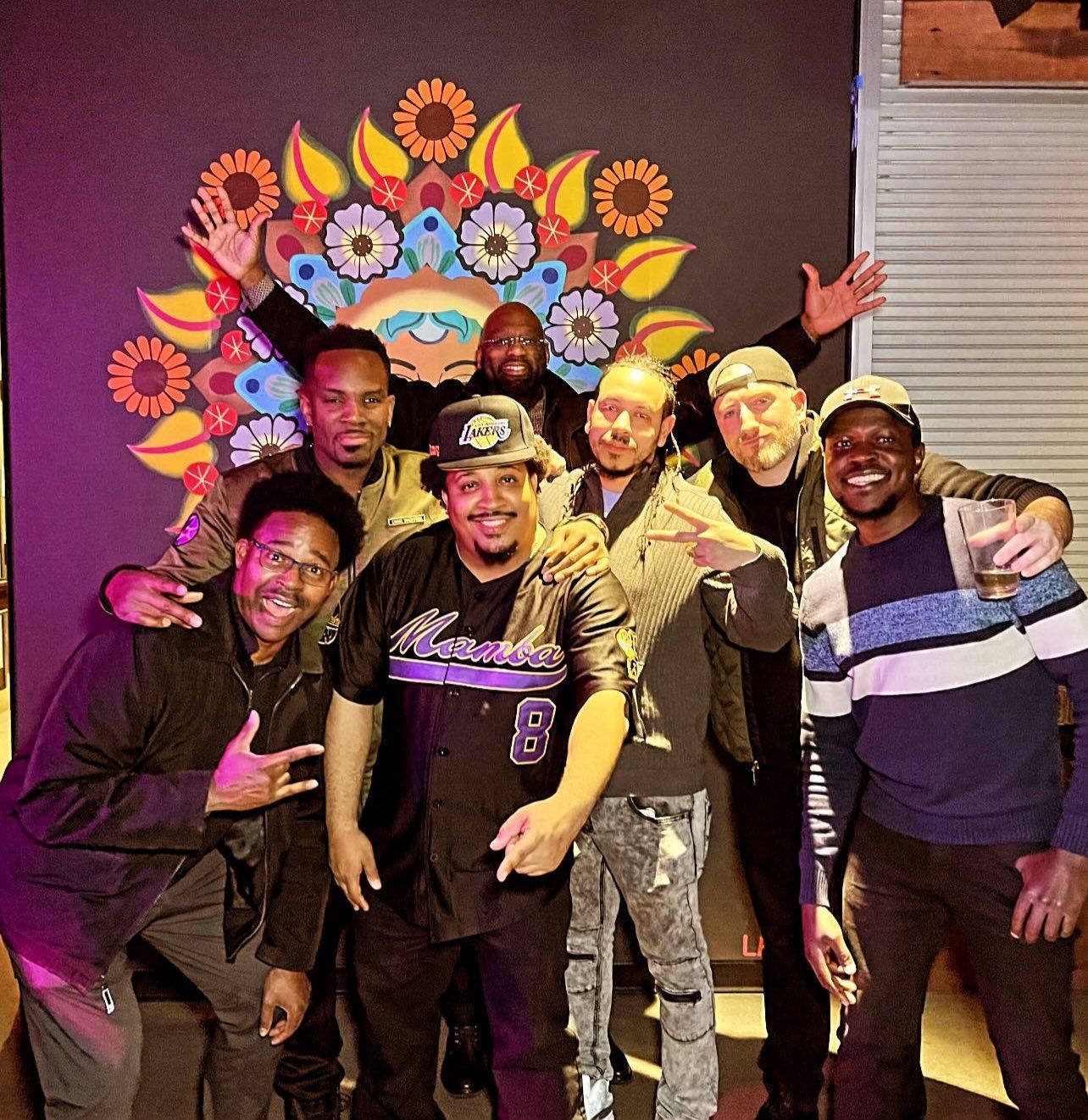 A group of men are posing for a picture and one of them has the number 8 on his shirt