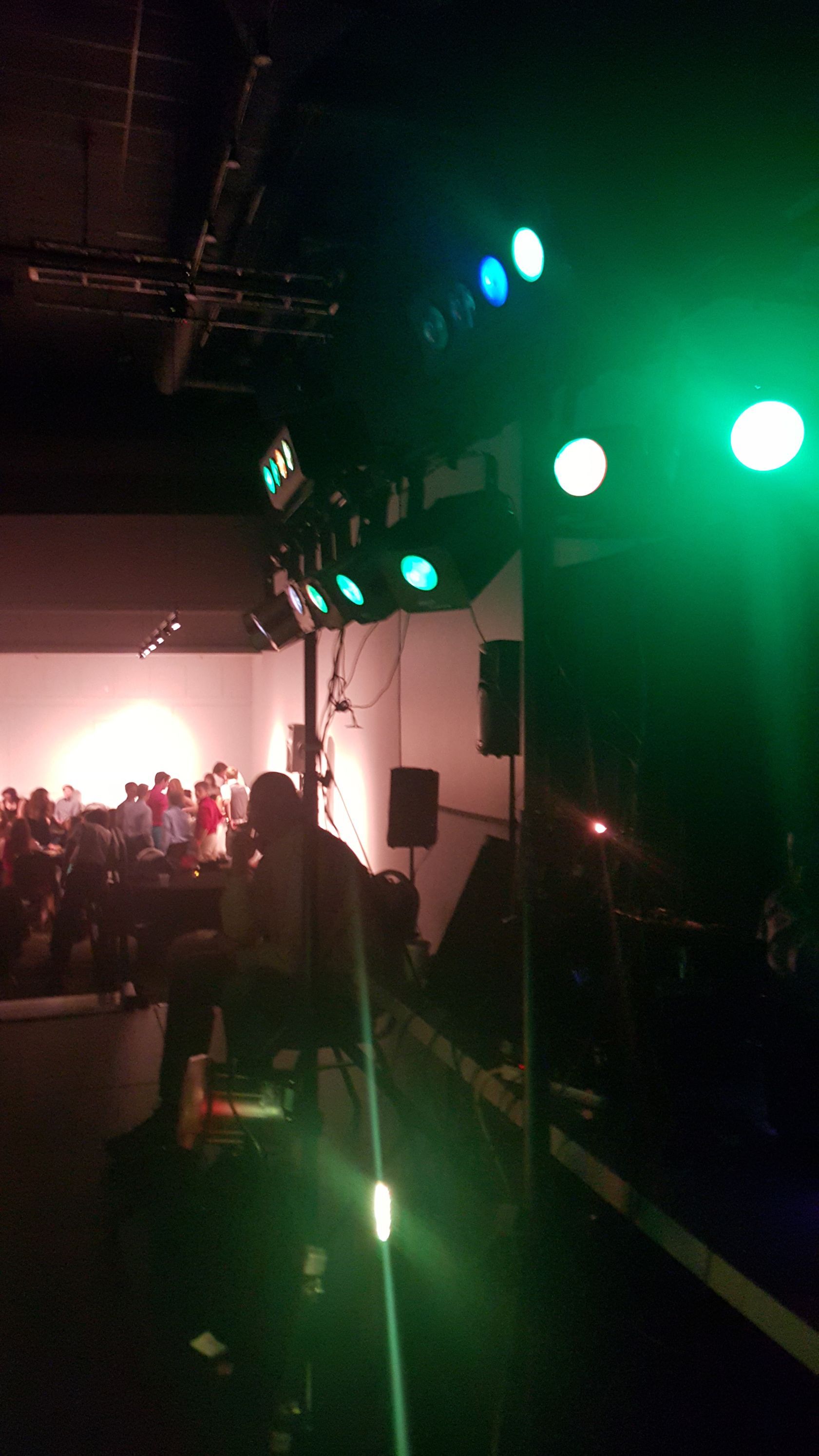 A group of people are sitting in a dark room with green lights.