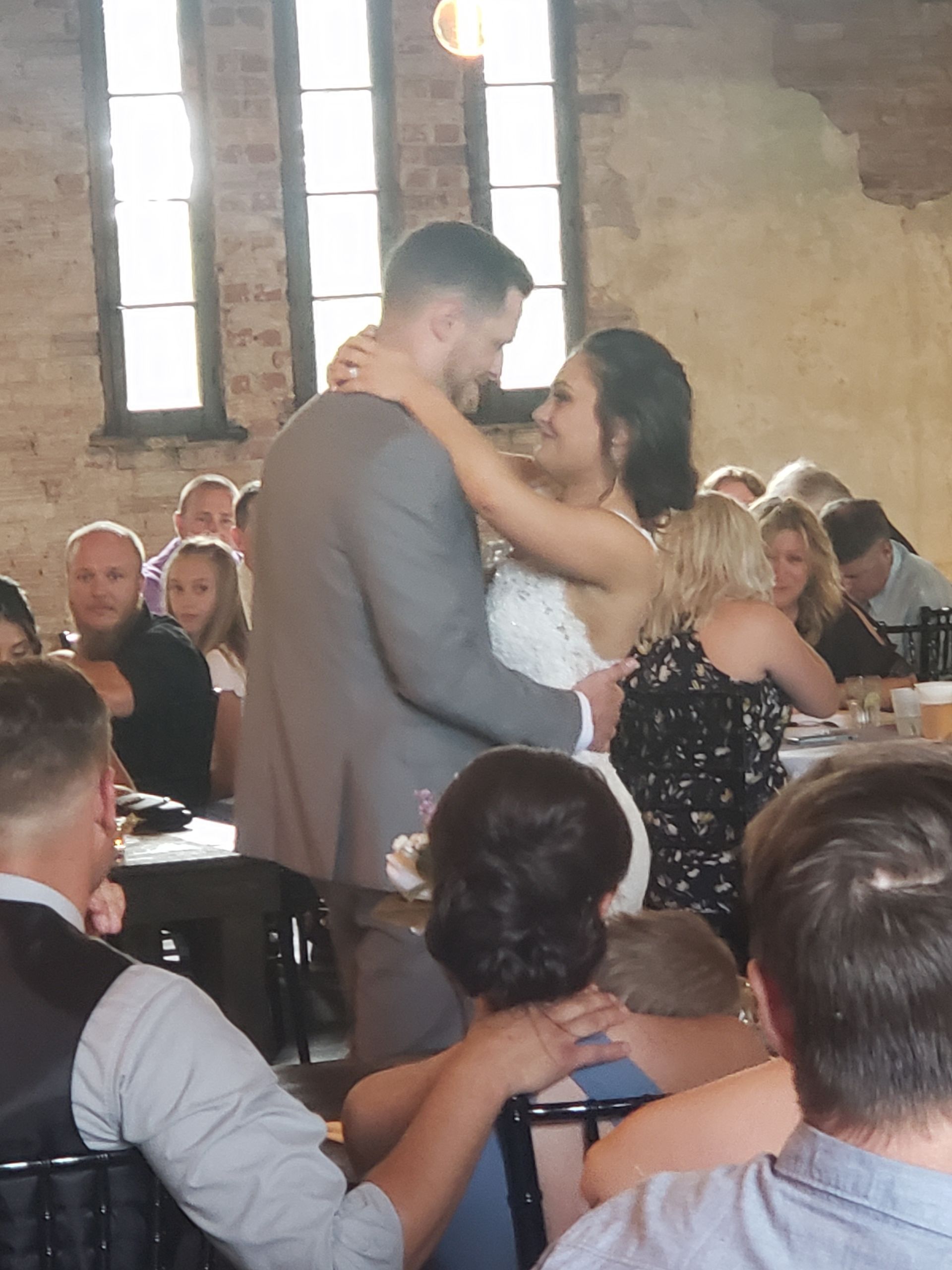 A bride and groom are dancing in front of a crowd of people