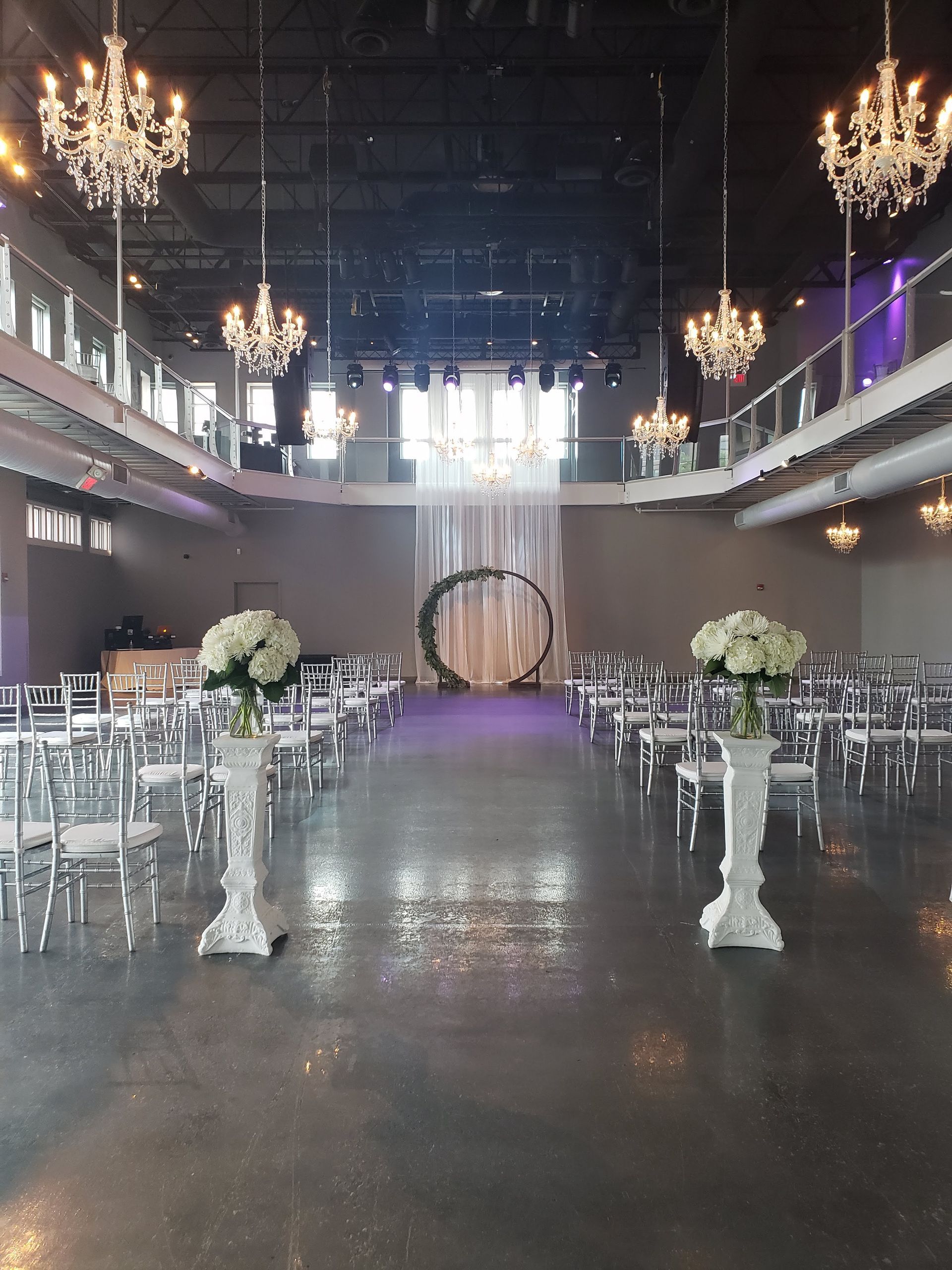 A large room filled with chairs and flowers for a wedding ceremony.