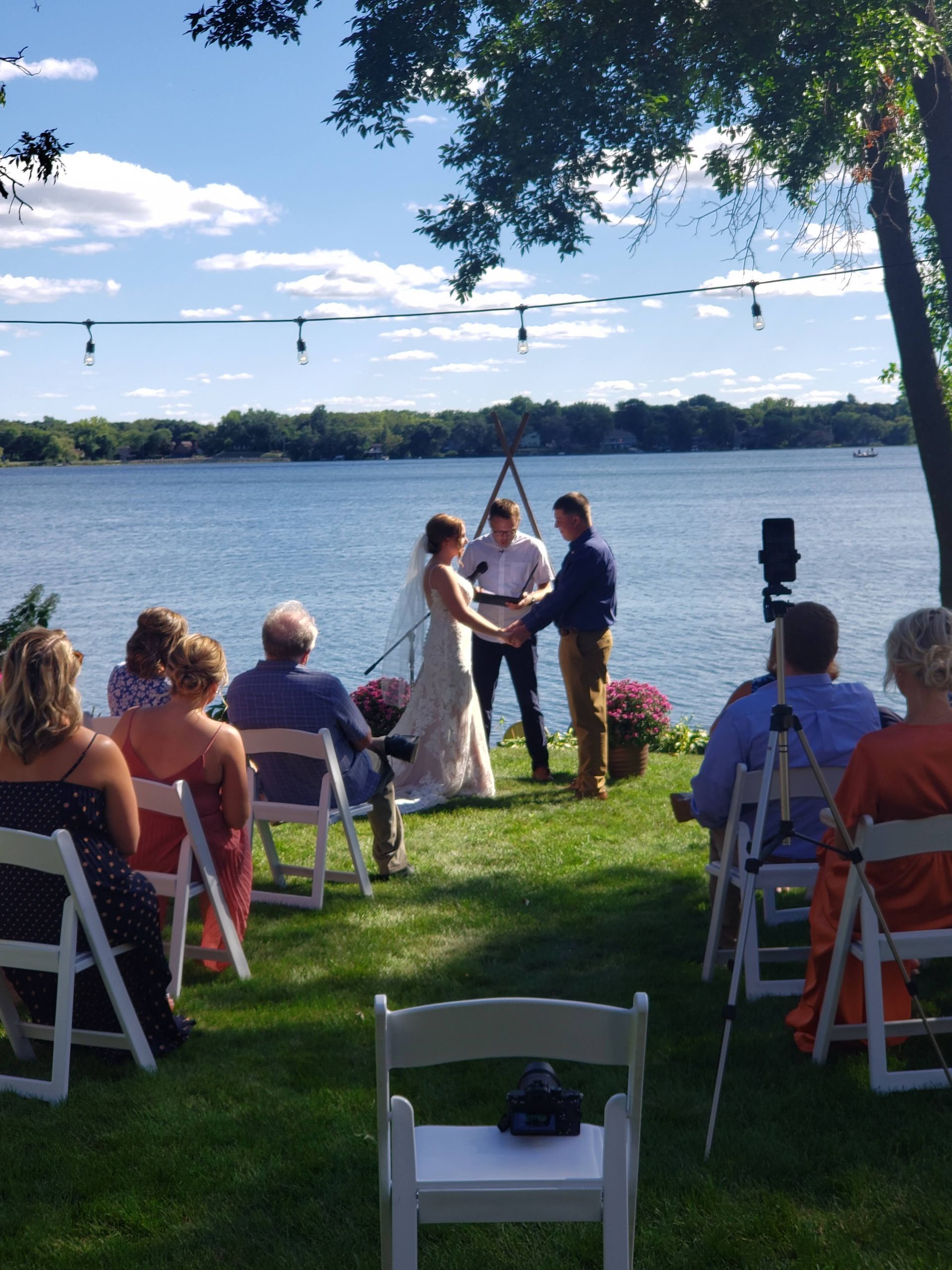 A bride and groom are getting married in front of a lake