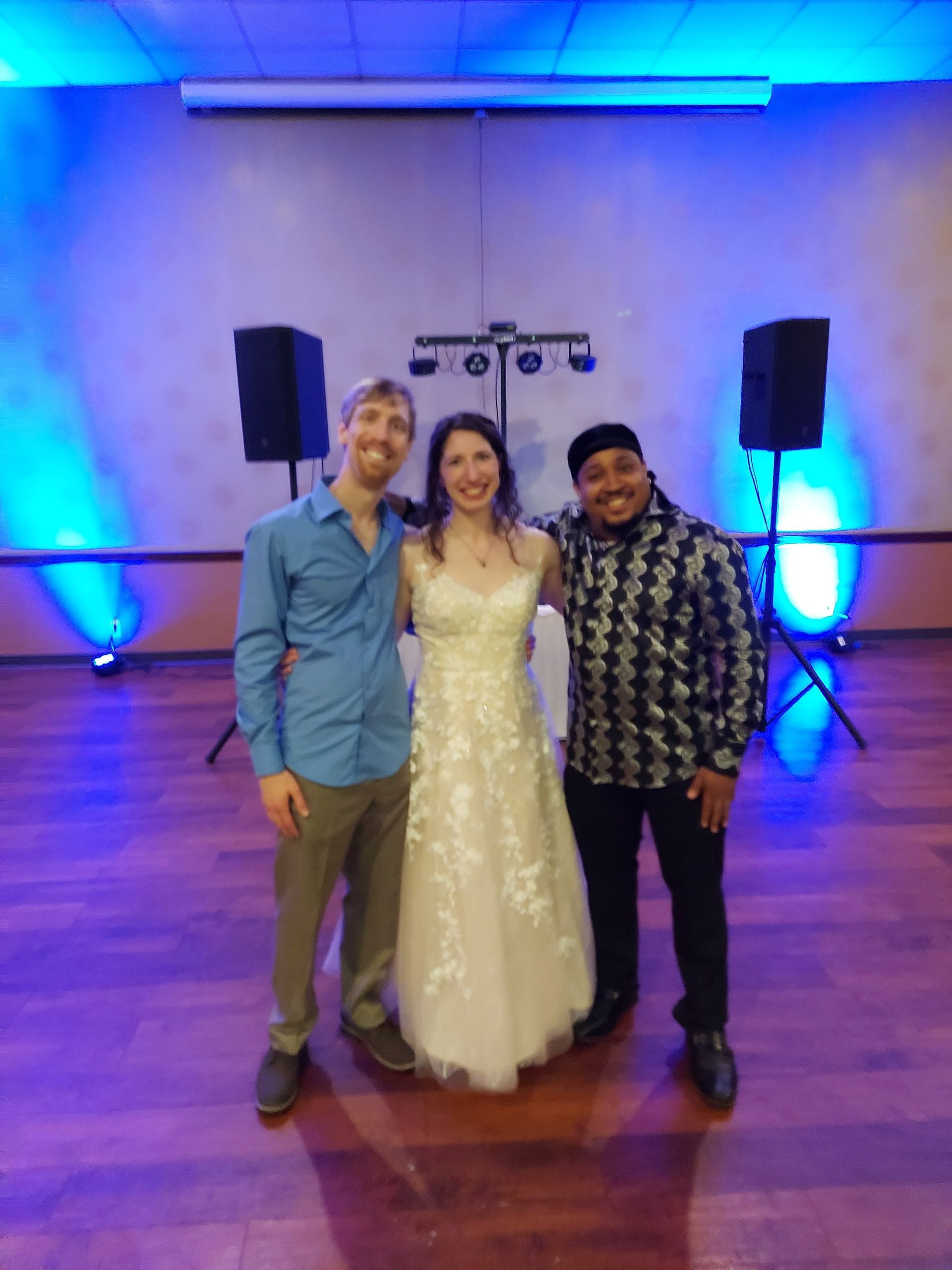 A bride and groom pose for a picture with two men