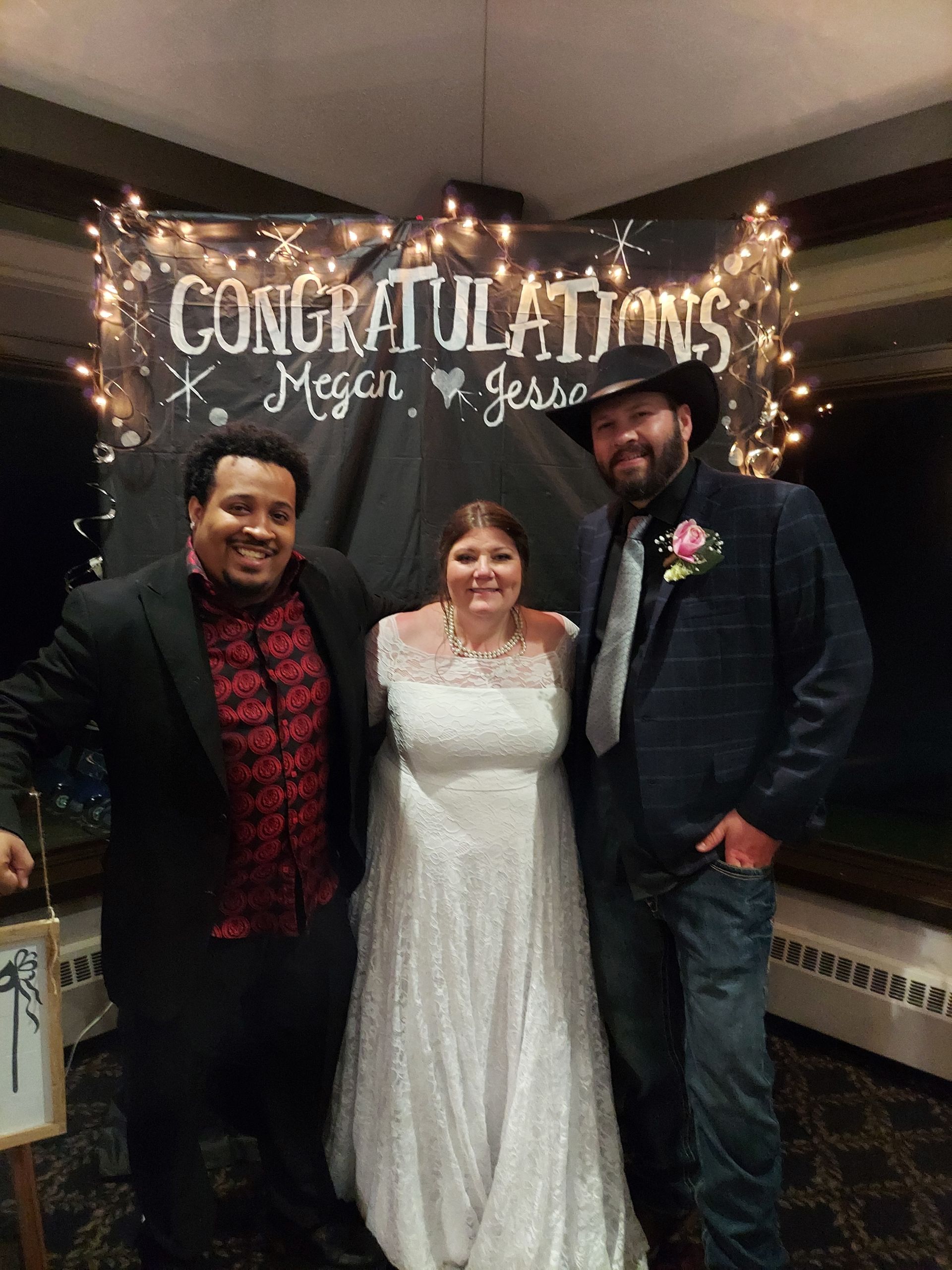 A bride and groom are posing for a picture with two men in front of a sign that says `` congratulations ''.