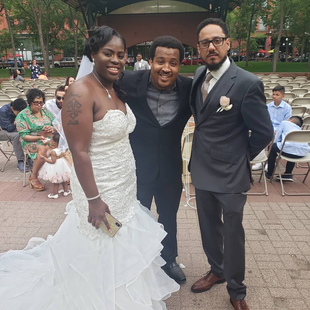 A bride and groom are posing for a picture with two men