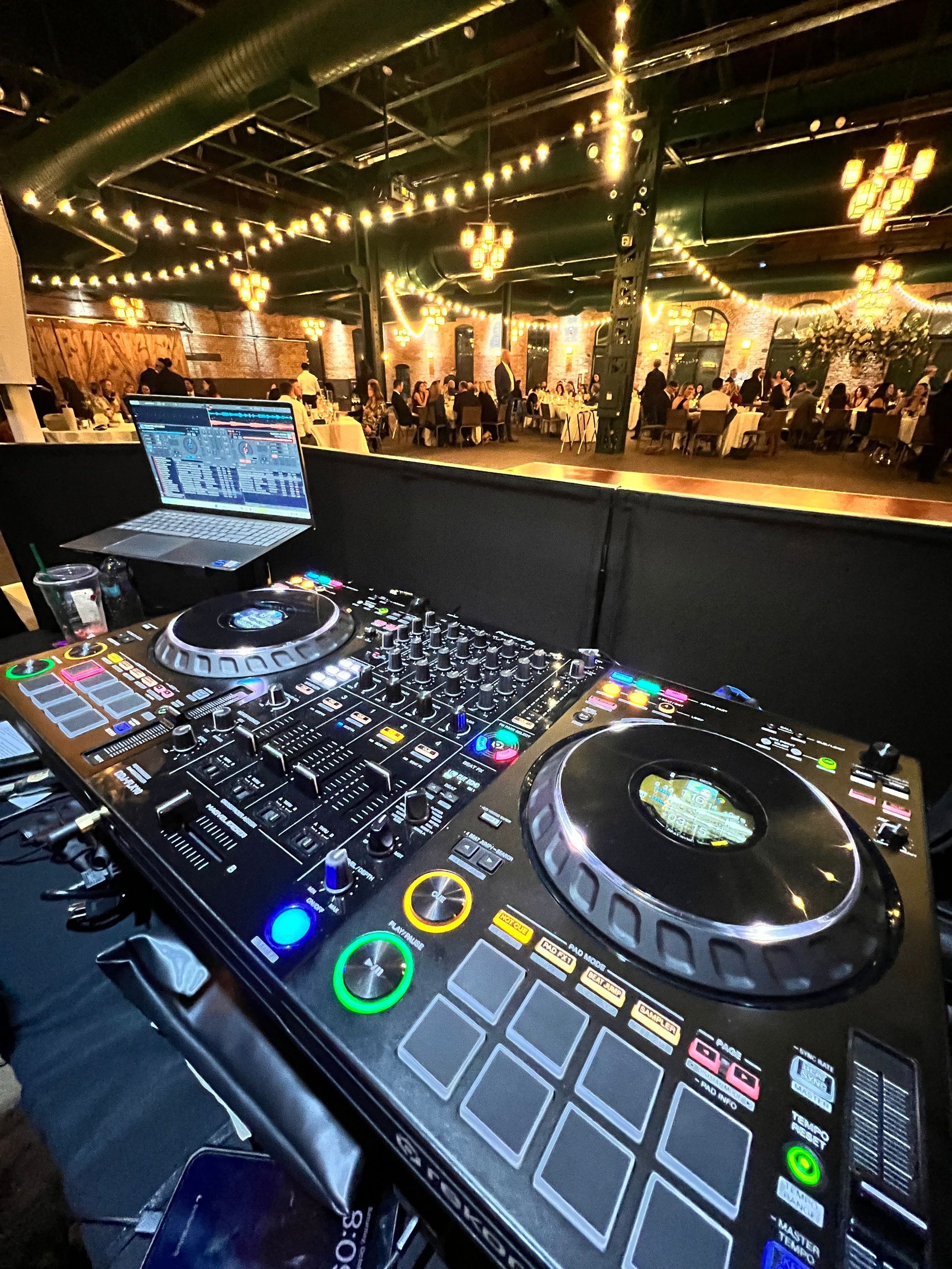 A dj 's controller is sitting on a table in a large room.