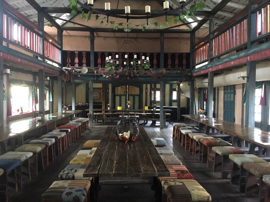 A large room with a long wooden table and stools.