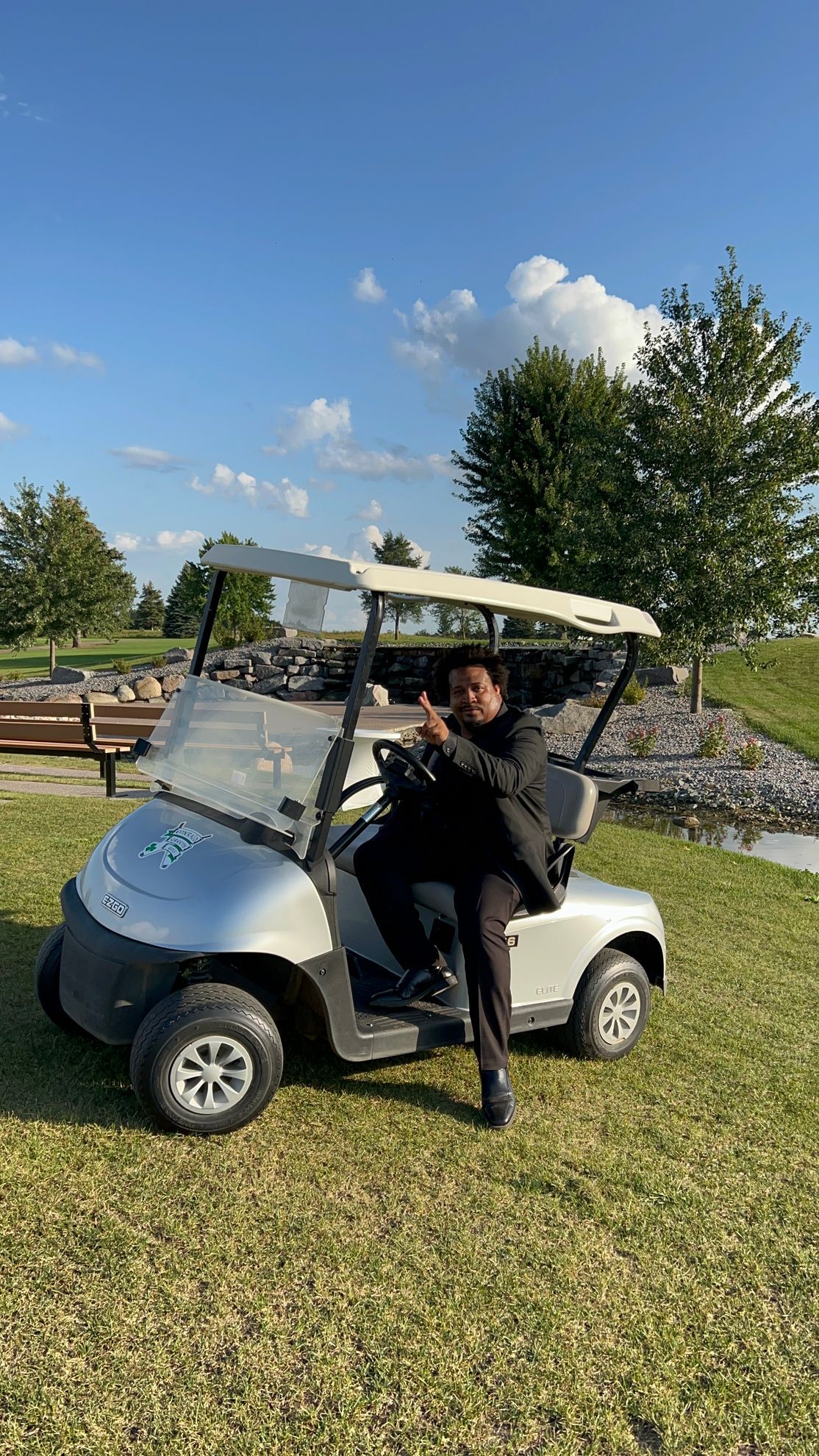 A man is sitting in a golf cart on a lush green field.