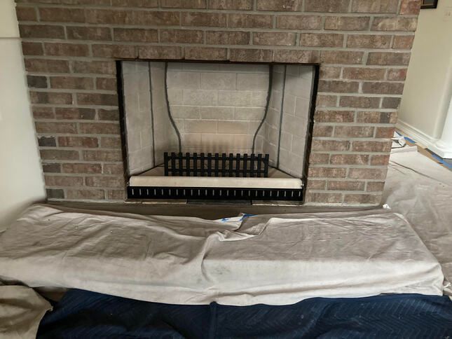 Brick fireplace interior with fire grate, covered hearth.