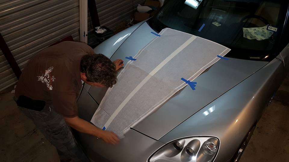 Worker applying decal to silver car