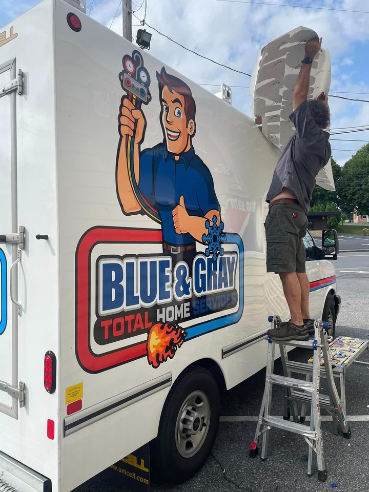 A man is standing on a ladder next to a blue and granite truck.