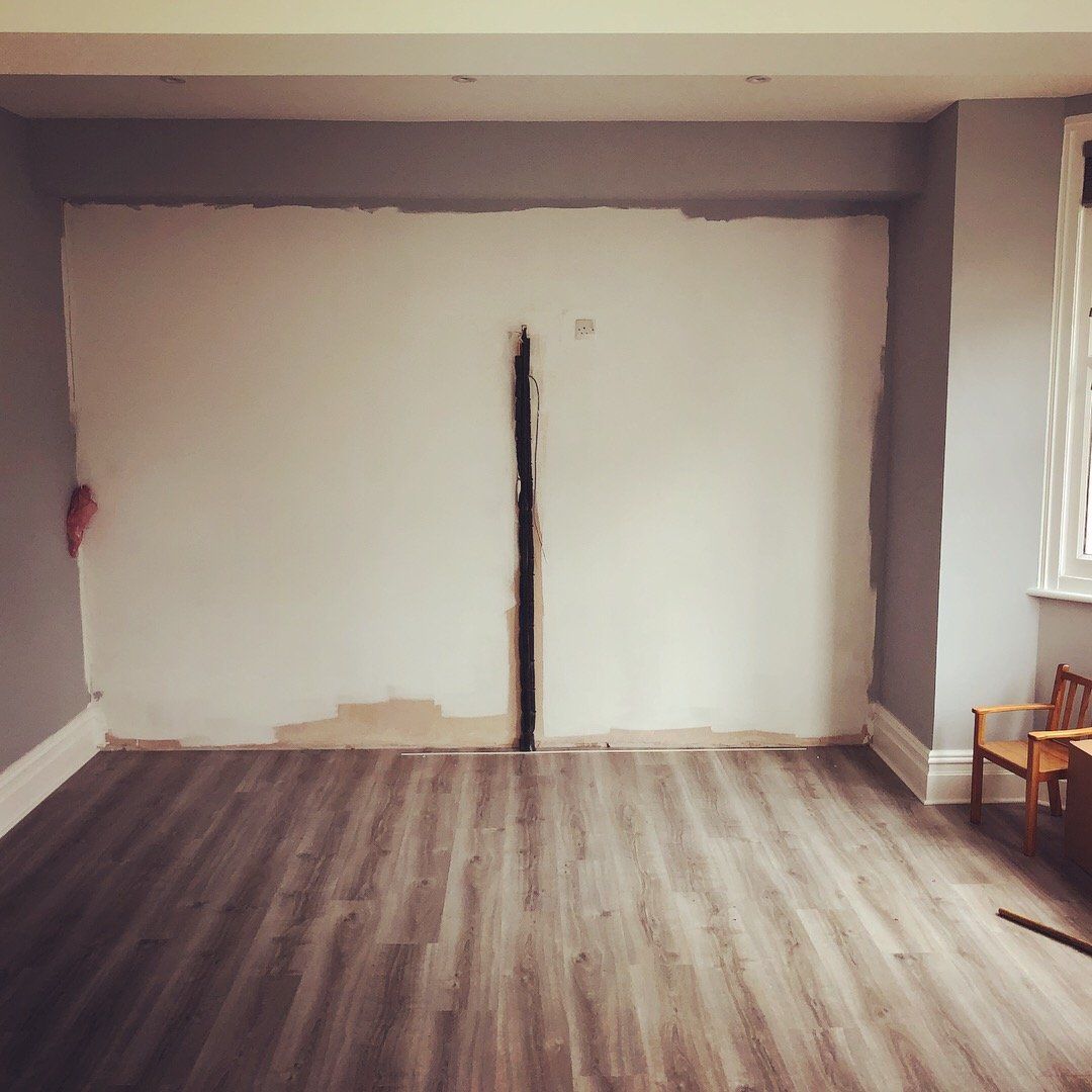 An empty room with a wooden floor and white walls