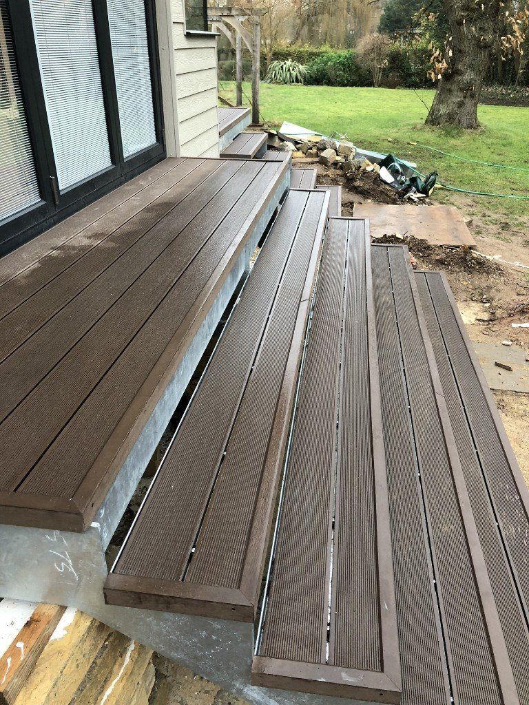 A wooden deck with stairs leading up to a house.